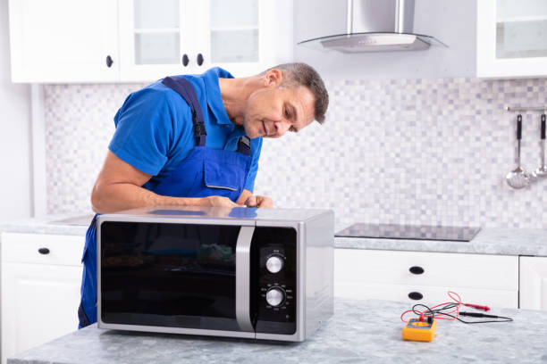 Technician Repairing Microwave Oven In Kitchen